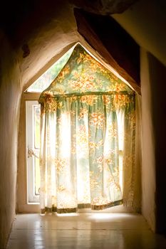 old cottage window with light creeping in behind the curtain