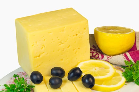 Piece of the yellow porous cheese, the cut slices of cheese, lemon and olives. Are presented on a white background.