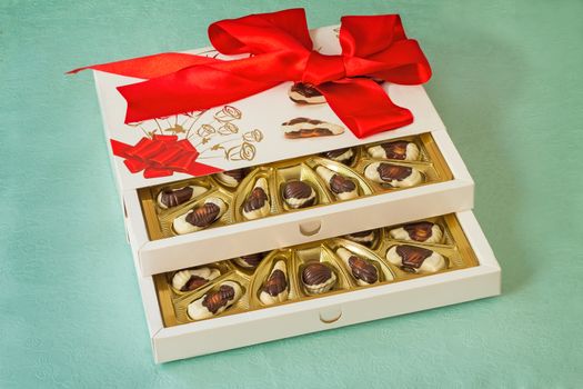 A beautifully decorated and tied with a ribbon box of chocolates, gift by a holiday, celebration, anniversary.