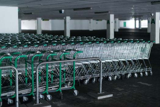 Rows of shopping carts in abandoned car park near entrance of closed supermarket due to public holiday