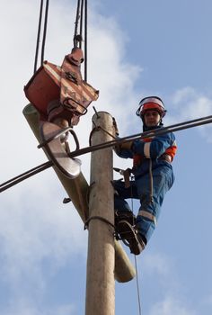 electrician raises the wire on top of an electricity pylon with the use of mobile crane