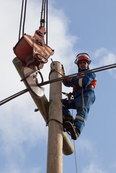 electrician raises the wire on top of an electricity pylon with the use of mobile crane 