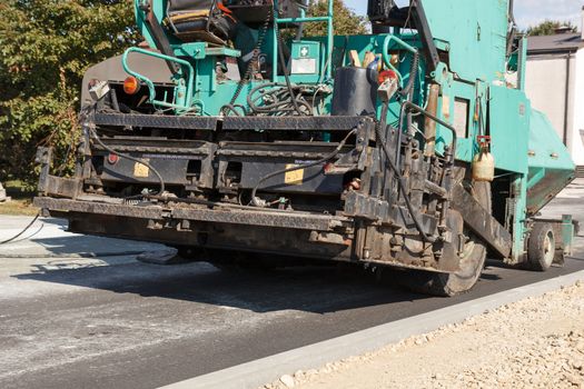 A working blue and black asphalt paving machine