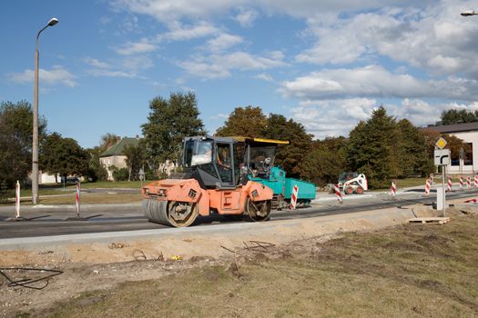 An asphalt paving construction site with machines near housing