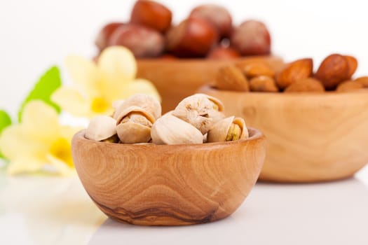 Pistachio, almonds, hazelnut with flowers in the wooden bowl.