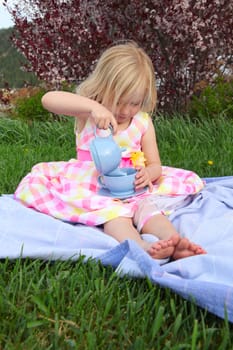 Little blond girl having a garden tea party