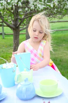 Little blond girl having a garden tea party