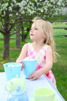 Little blond girl having a garden tea party