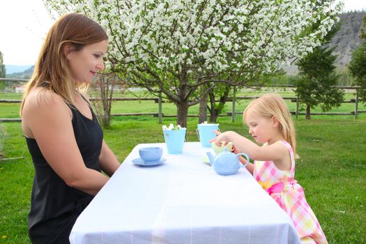 Little blond girl having a garden tea party