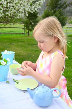 Little blond girl having a garden tea party