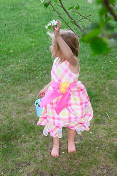 Little blond girl picking blossoms from a crab apple tree
