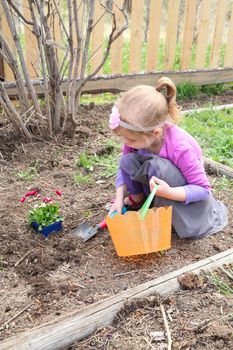 Little girl planting flowers in spring weather