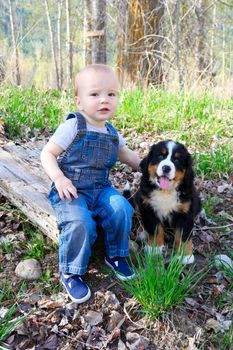 Toddler in denim overall playing with his puppy