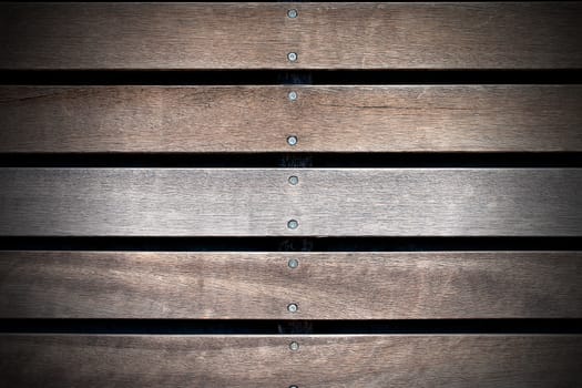 Wooden background with five brown and white boards and screws on black background