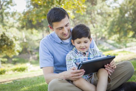 Handsome Mixed Race Father and Son Playing on a Computer Tablet Outside.