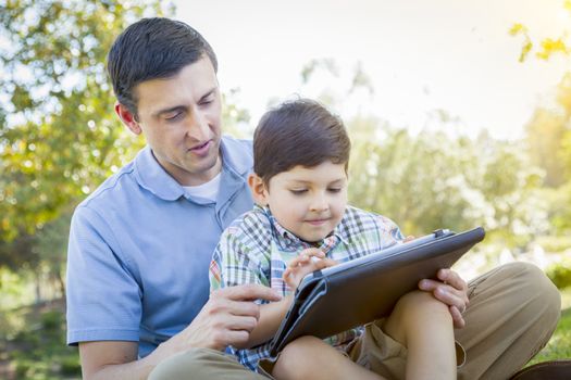 Handsome Mixed Race Father and Son Playing on a Computer Tablet Outside.