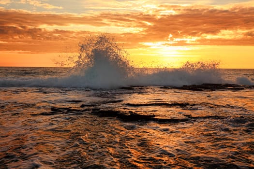 Ocean waves splash onto the rock ledge