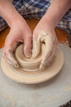 Hands of a potter, creating an earthen jar on the circle