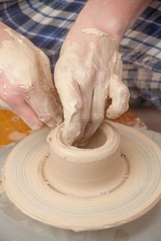 Hands of a potter, creating an earthen jar on the circle