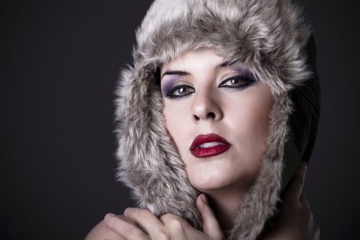 Female green-eyed brunette with fur hat, winter concept