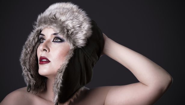 Female green-eyed brunette with fur hat, winter concept