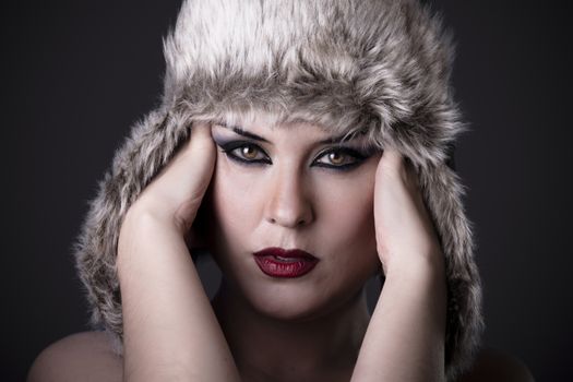 Girl with headache and Russian hat on dark background