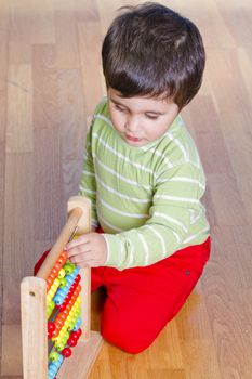 Caucasian baby in green shirt playing with bright colorful blocks