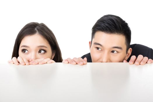 Asian business man and woman hide under the table and looking somewhere.