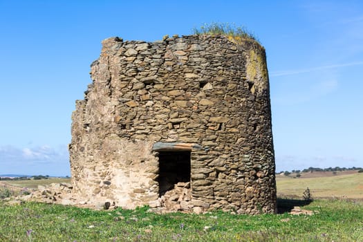 Remnants of a windmill in Field, on blue sky background