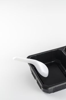 empty black plastic tray and spoon on a white background