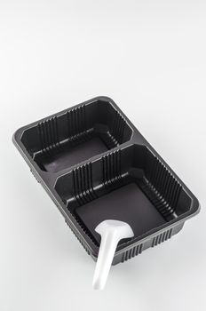 empty black plastic tray and spoon on a white background