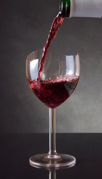 Pouring red vine into a broken glass