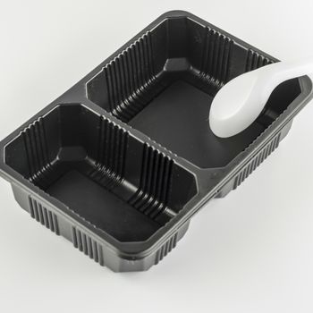 empty black plastic tray and spoon on a white background