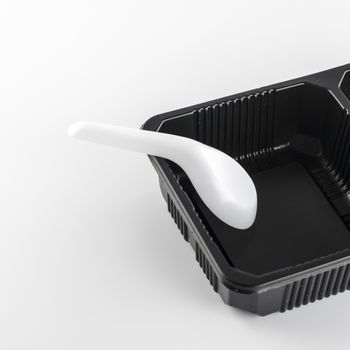 empty black plastic tray and spoon on a white background