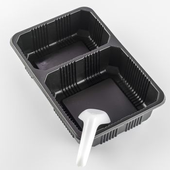 empty black plastic tray and spoon on a white background