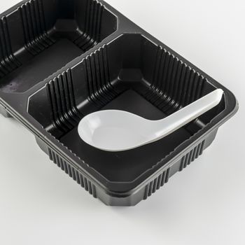 empty black plastic tray and spoon on a white background