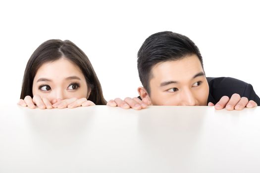 Asian business man and woman hide under the table and looking somewhere.