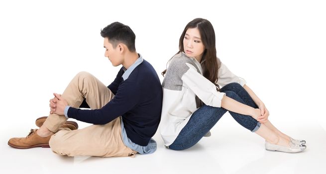 Young Asian couple sit on ground back to back and one turn back to care on studio white background.