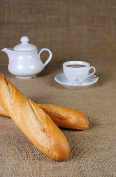 Wheat baguette on sackcloth and a cup of coffee