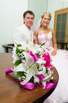 wedding photo. Bridal bouquet on background of happy newlyweds
