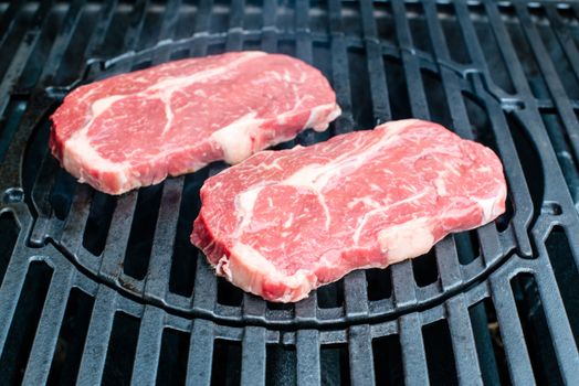 two entrecote beef steaks freshly put on the bbq and waiting to be grilled