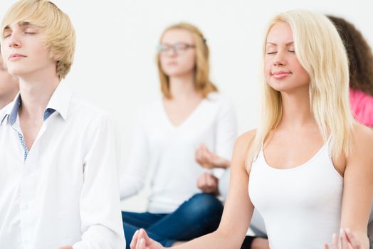 attractive young woman, meditating with closed eyes, group meditation
