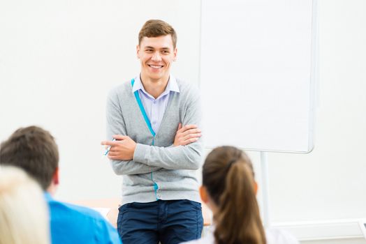 young teacher man talking with students in the classroom