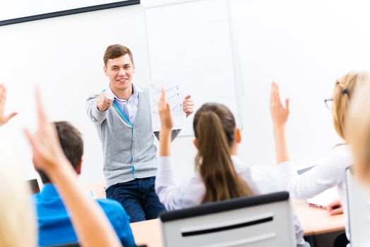 young teacher man talking with students in the classroom