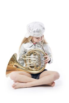 sitting young girl with cap playing french horn against white background