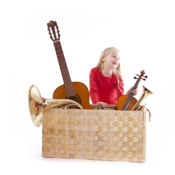 young girl with musical instruments in box against white background