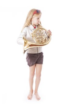 young girl playing french horn against white background