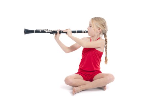 young sitting girl in red playing clarinet against white background