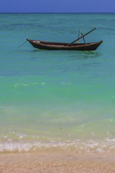A solitary country fishing boat anchored near the shoreline in the calm  emerald green waters of andaman sea in havelock island , andamans, india presents a picture of tranquility