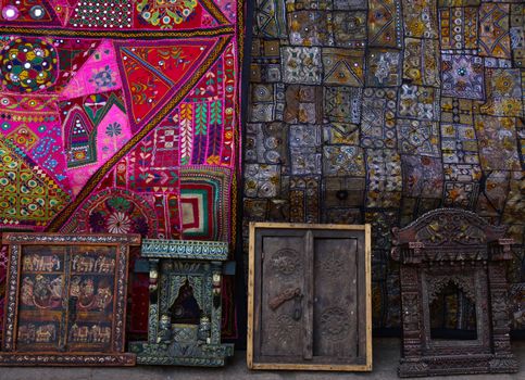 Two Multicoloured Patchwork Quilts with Hand Ebroidery and Mirror inlays , one in bright colors and second in muted colors. Handmade Small wooden carved ornamental windows with Intricate Carvings or Paintings of miniatures Floral designs and images of animals hindu gods for sale  in Jaisalmer Fort, Rajasthan, India